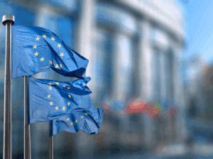 Flags of the European Union flying in front of a building.