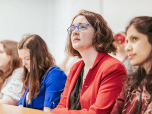 A woman in a lecture hall looking up at something off camera