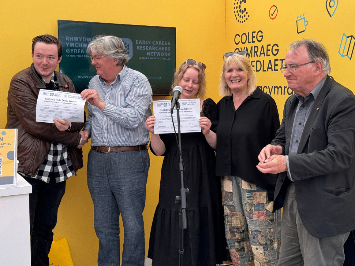 Five people in a row, two of them holding certificates.
