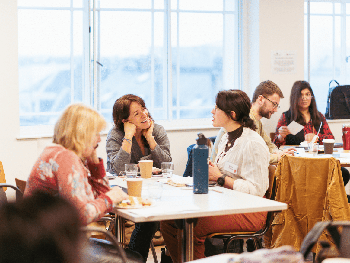 A room with two tables, people sitting around them deep in conversation