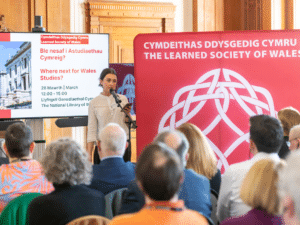 A woman holding a microphone talking to an audience.