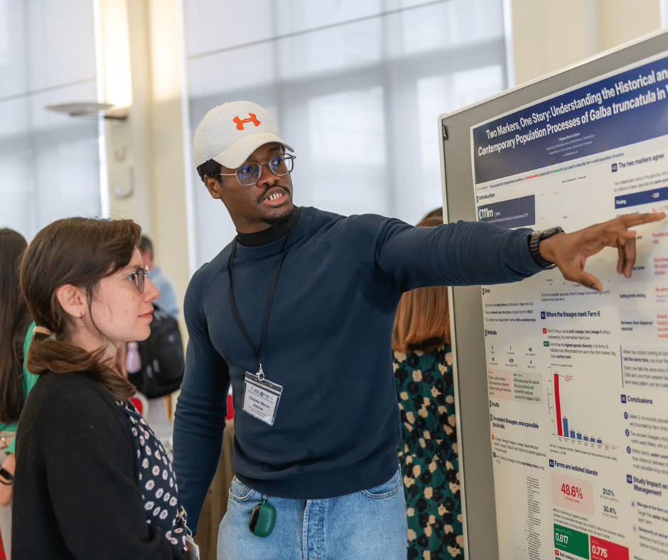 A man pointing at a poster while talking to a woman.