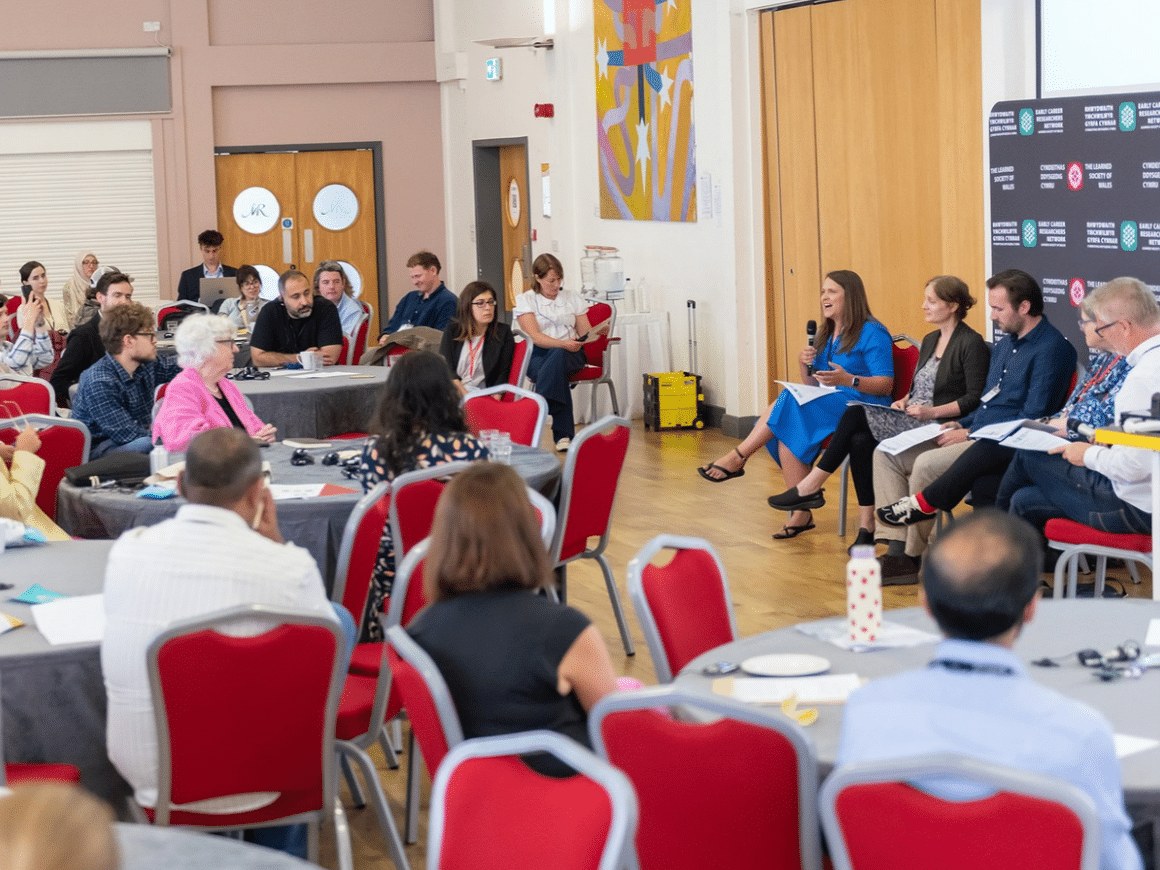 A panel discussion taking place in a large crowded room.
